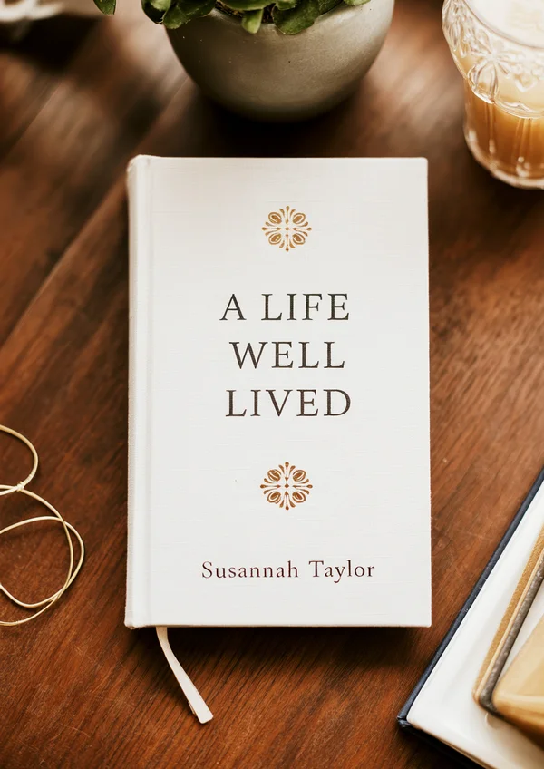 A beautifully bound linen hardcover memoir book titled 'A Life Well Lived' on a wooden desk